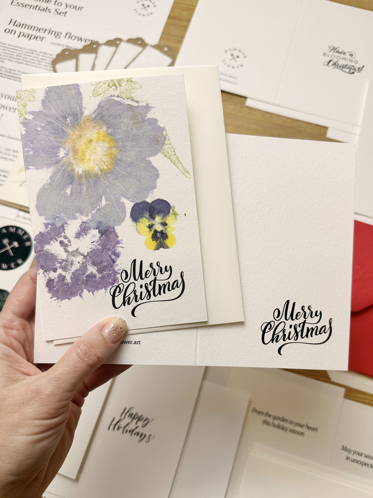 Finished purple botanical Christmas card beside an undecorated card, showing a flower-hammering example